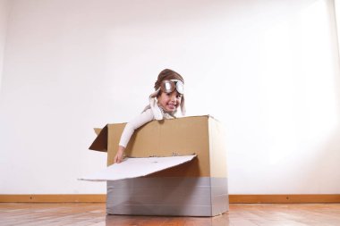 küçük çocuk pilot el yapımı karton kutu uçağın içinde evde oynarken olarak giyinmiş