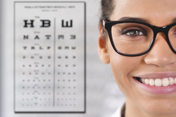 幸せ笑顔の女性で 眼鏡をかけて眼鏡と視力検査用スネレン視力表に立って光中心の部分的なビュー — ストック写真