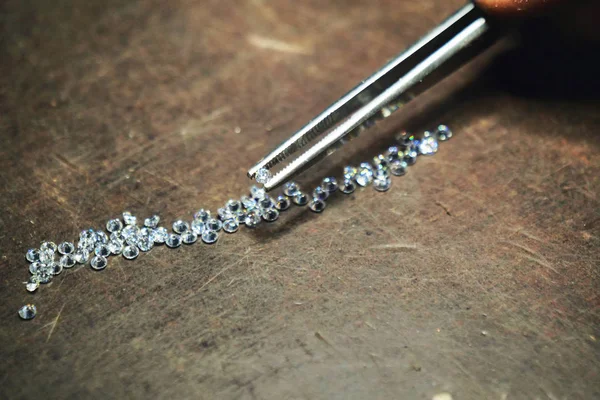 Close up of a hand of a goldsmith who with professional tweezers, checks the diamonds that he will use for the production of handmade luxury jewelery. Concept of: tradition, luxury, jewelry.