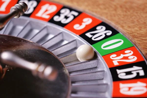 Macro shot of a roulette in a casino where the ball goes to the green or red or black number. People having bet and bet money may have won lost badges. Concept of: fate, gambling, luck, destiny.