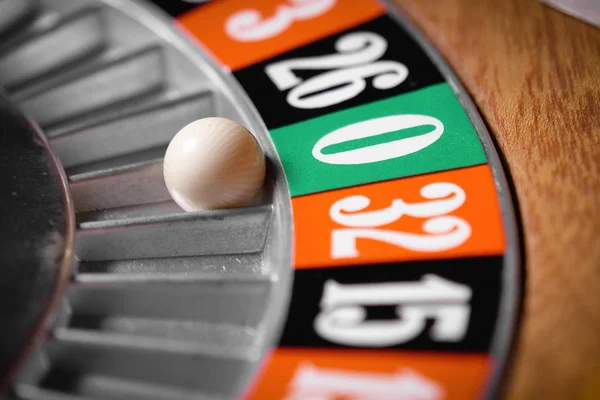 Macro shot of a roulette in a casino where the ball goes to the green or red or black number. People having bet and bet money may have won lost badges. Concept of: fate, gambling, luck, destiny.