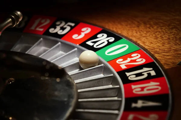 Macro shot of a roulette in a casino where the ball goes to the green or red or black number. People having bet and bet money may have won lost badges. Concept of: fate, gambling, luck, destiny.