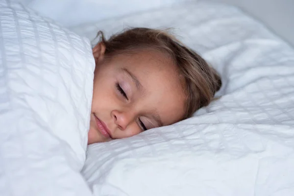 一个美丽的女孩睡觉 并有安静的梦想 在她的白色床上覆盖着毯子 这个女孩笑了 因为她很放松 睡得很好 爱睡觉 — 图库照片