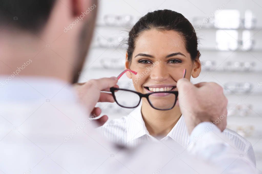 ophthalmologist man giving customer woman new glasses at optical center 