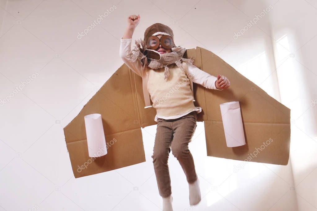 playful little boy dressed as aviator pilot in handmade cardboard box plane 