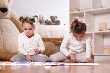 Keçeli kalemler ile renk ve sanatsal çizimler yapmak onların yatak odasında yerde yatan iki küçük kız portresi. Kavramı: Aile, renk, yaratıcılık, sanat, mutluluk ve eğitim.