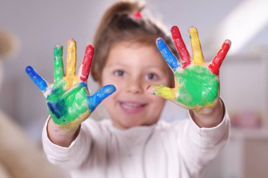 Ellerini tüm boya ile renkli gösterilen yatak odasında küçük bir kız portresi. Kavramı: renk, yaratıcılık, sanat, mutluluk ve eğitim.