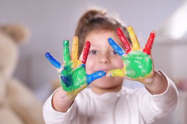 Ellerini tüm boya ile renkli gösterilen yatak odasında küçük bir kız portresi. Kavramı: renk, yaratıcılık, sanat, mutluluk ve eğitim.