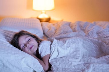 Küçük bir kız gece onun yatak odasında uyuyor ve pencereden gelen ve tatlı yüzüne aydınlatma ay ışığı görüyorum. Kavramı: huzurlu rüyalar, iyi uyku, dinlenme, ev.