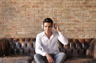 kulaklıklar müzik dinleme ve kameraya bakarak Beyaz tişörtlü yakışıklı esmer beyaz adam 