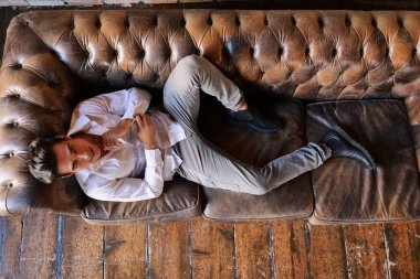 tam uzunlukta, kameraya bakmak şık esmer beyaz adamın beyaz gömlekli kanepeye, yalan üstten görünüm