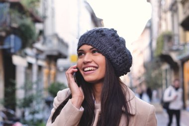 gülümseyen bere şapka ile hareket eden telefon içinde mutlu güzel beyaz esmer kadın 