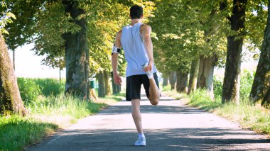 arkadan görünüşü sporcu ısınma egzersizleri bacaklar ile yapıyor