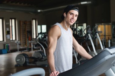 koşu bandı üzerinde duran ve kameraya bakarak ve kulaklık müzik dinleme beyaz adam