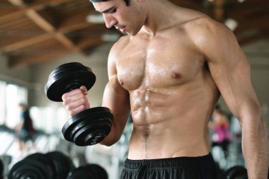 Salondaki, gömleksiz adam vücudu fit kalmak ve kasları tanımlamış olduğunuz için eğitiyor. Atlet ağır ağırlık ve yorgunluk yükseltir. Kavramı: spor, spor salonu, kas ve fitness