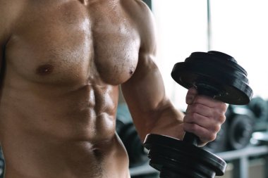 Salondaki, gömleksiz adam vücudu fit kalmak ve kasları tanımlamış olduğunuz için eğitiyor. Atlet ağır ağırlık ve yorgunluk yükseltir. Kavramı: spor, spor salonu, kas ve fitness