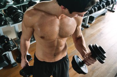 Salondaki, gömleksiz adam vücudu fit kalmak ve kasları tanımlamış olduğunuz için eğitiyor. Atlet ağır ağırlık ve yorgunluk yükseltir. Kavramı: spor, spor salonu, kas ve fitness