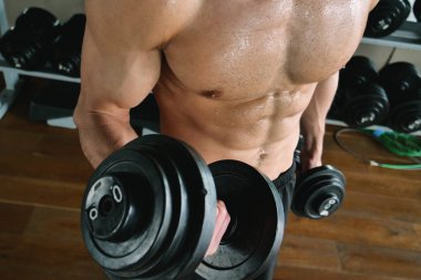 Salondaki, gömleksiz adam vücudu fit kalmak ve kasları tanımlamış olduğunuz için eğitiyor. Atlet ağır ağırlık ve yorgunluk yükseltir. Kavramı: spor, spor salonu, kas ve fitness