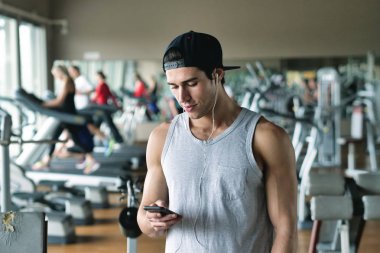 Kendini güç ile şarj etmek için bir adam onun iş için hazırlanıyor ve onun kulaklıktan biraz müzik koyarak bir spor salonunda portresi. Kavramı: spor, kişisel antrenör ve fitness ve müzik