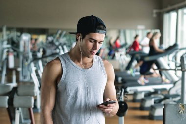 Kendini güç ile şarj etmek için bir adam onun iş için hazırlanıyor ve onun kulaklıktan biraz müzik koyarak bir spor salonunda portresi. Kavramı: spor, kişisel antrenör ve fitness ve müzik