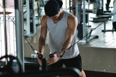 Salondaki, gömleksiz adam vücudu fit kalmak ve kasları tanımlamış olduğunuz için eğitiyor. Atlet ağır ağırlık ve yorgunluk yükseltir. Kavramı: spor, spor salonu, kas ve fitness