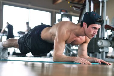 Bir spor salonunda bir yelek giyen bir çocuk vücudu fit kalmak ve kasları ücretsiz vücut egzersizleri ile tanımlamış olduğunuz için eğitiyor. Kavramı: spor, spor salonu, kas ve fitness