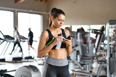 Güzel genç kadın gülümsüyor iken bir mesajı okumak ve müzik dinlemek, bir mesaj yazmak, sosyal ağlar spor bakmak.