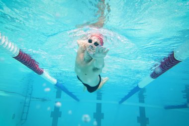 Bir profesyonel yüzücü serbest bir havuzda yüzerek yarışı kazanmak için çaba ve özveri ile eğitiyor. Kavramı: spor, yüzme havuzu, rekabet, fitness.