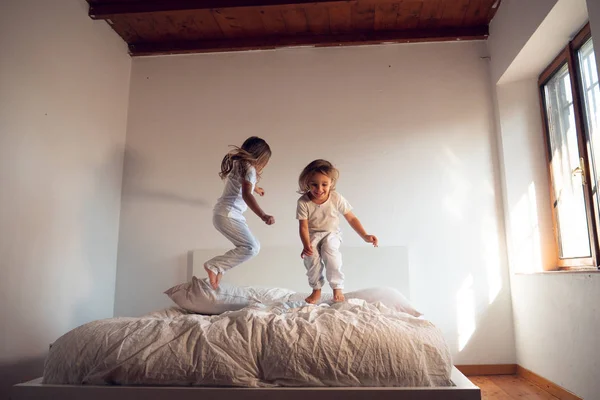 Dua Saudara Perempuan Mengenakan Piyama Putih Melompat Tempat Tidur Dan — Stok Foto