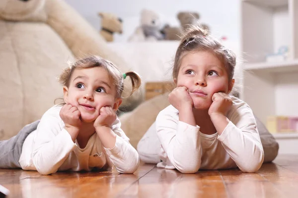 Két Nővére Feküdt Padlón Hálószobában Mosolyogva Háttérben Kitömött Állatok Dollhouse — Stock Fotó