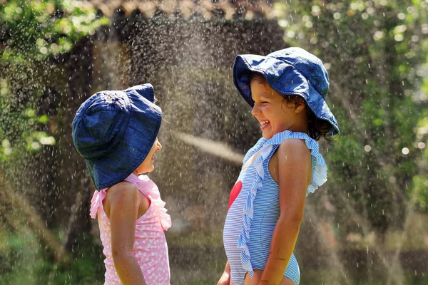 水と庭で遊ぶ二人の少女 二人の女の子を実行 濡れるし — ストック写真