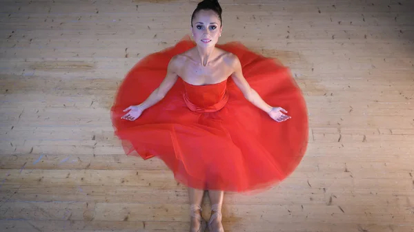 一个美丽的浅色芭蕾舞演员的肖像 穿着郁郁葱葱的红色礼服 坐在木地板上 顶视图 概念芭蕾舞演员 苗条的饮食轻的女人 美丽的身材 健康的生活方式 灵活性 — 图库照片