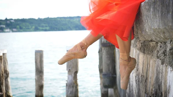 一个美丽的浅色芭蕾演员的肖像 穿着郁郁葱葱的红色礼服 坐在一个石墩上 芭蕾舞演员 轻盈的女人 柔韧性 美丽的身材 健康的生活方式 — 图库照片
