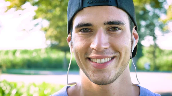 Portret Uśmiechający Się Przystojny Młody Mężczyzna Słuchawki Cap Patrząc Kamery — Zdjęcie stockowe