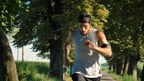 运动员男子跑在户外与手机臂章在手 — 图库照片