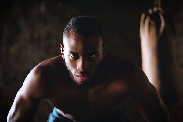 portrait of handsome shirtless muscular boxer african man looking at camera and doing push-ups