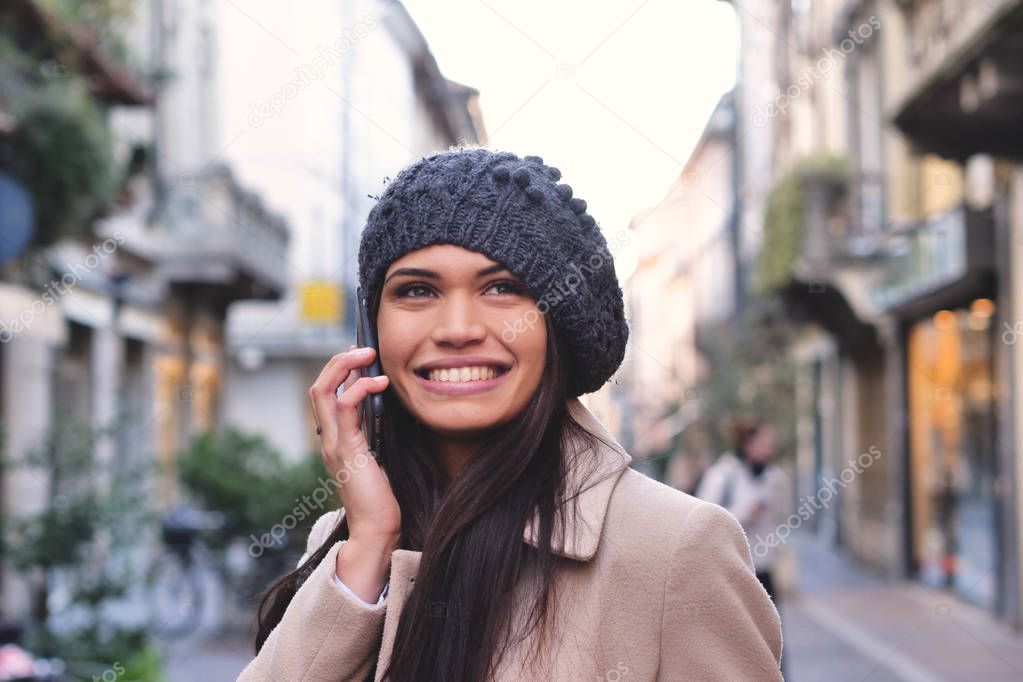 smiling happy beautiful Caucasian brunette woman in beret hat with mobile phone 