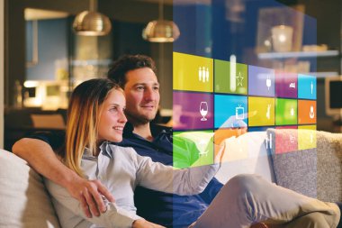 Bir çift kanepede oturan ev wi-fi, Isıtma, aydınlatma, holografi üzerinden televizyon gibi tüm fonksiyonlarını kontrol eder. Kavramı, ev otomasyon, otomasyon sistemleri, gelecek, teknoloji.