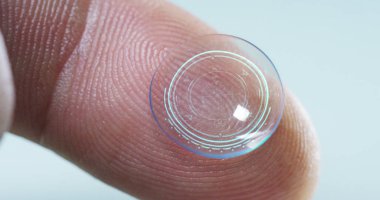 Makro çekim bir kontakt lens teknolojisi ile gözleri ve artış diyoptriden daha iyi görmek için küçük parça tutan bir parmak. Konsept: göz muayenesinde, optik, üstün teknoloji