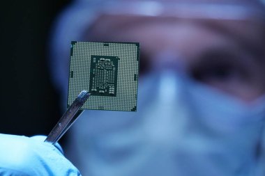 Ultra Modern elektronik imalat fabrikası tasarım mühendisi olarak steril Coverall tutan mikro yongasında fütüristik holografi, Internet cyber security sembolleri ile.