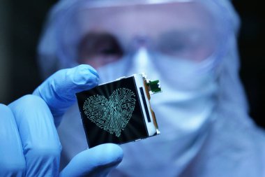 Ultra Modern elektronik imalat fabrikası tasarım mühendisi olarak steril Coverall tutan mikro yongasında fütüristik holografi sembolleri ile. aşk için bilgisayar.