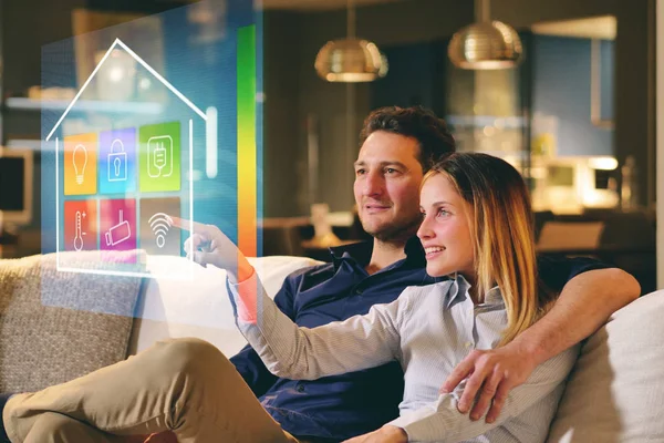 一对坐在沙发上的夫妇通过全息术控制着房子的所有功能 如无线网络 家庭自动化 自动化 — 图库照片