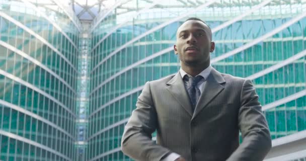 モダンなガラスの腕を持つ建物に深刻なアフリカ ビジネス人を越え スロー モーション ビデオ — ストック動画
