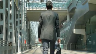 Genç yakışıklı işadamı (öğrenci) mavi gömlekli, Bagaj ile gelir, bir ceket istasyonunda Havaalanı almıştır. Konsept: yeni iş seyahat dünya, iletişim, kişiler, el çantası,.