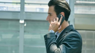 Gülümseyerek, havaalanında istasyonunda telefonda konuşurken bir genç yakışıklı işadamı (öğrenci) bir takım, portresi. Konsept: yeni iş, seyahat dünya, iletişim, kişiler, iş anlaşması