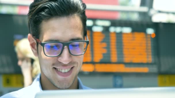 年轻的英俊商人 穿着一件蓝色衬衫 在桌子上与笔记本电脑一起工作 戴着眼镜 面带微笑 新业务 业务关系 职业发展 在线工作 — 图库视频影像