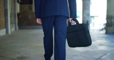 bir işadamı zarif elbise yavaş Meydanı'nda yürüyüş bavulla. Konsept: rise güç, yol gitmek, kariyer, iş, siyaset, aspirasyon