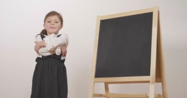 Küçük bir karatahta önünde bir öğretmen kollarındaki katlanmış ve gülümsüyor tutar olarak mutlu bir kız kılığında. Kavramı: eğitim, okul, iş ve çalışma için aşk.