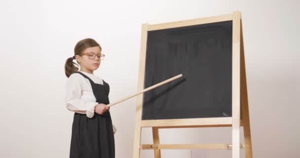 Una Niña Feliz Vestida Maestra Delante Una Pequeña Pizarra Sostiene — Vídeo de stock