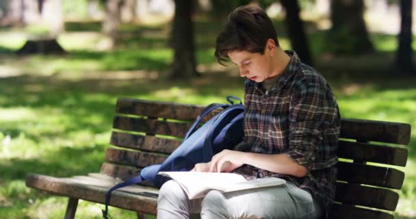 Відео Хлопчика Підлітка Який Навчається Парку Читає Сидячи Лавці — стокове відео
